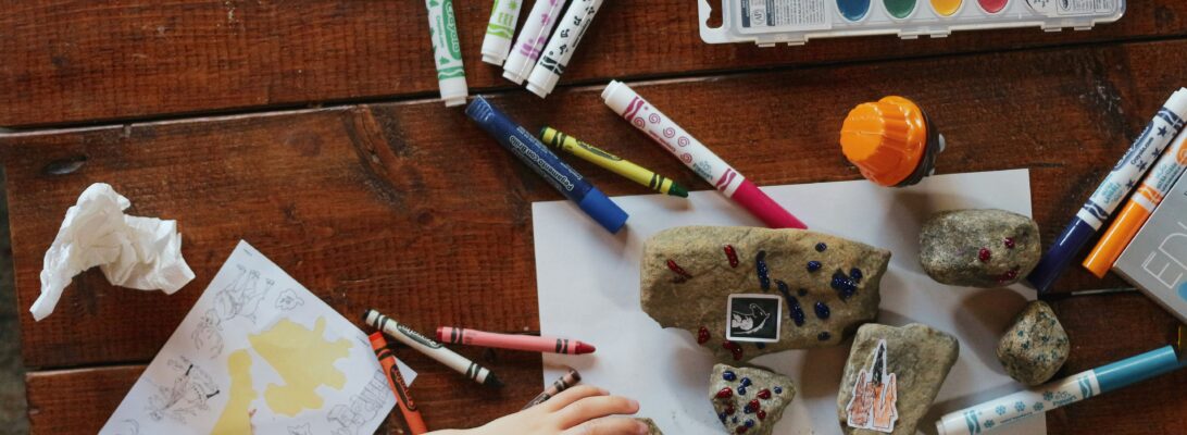 A photo of a child being creative at a big desk covered in art materials