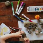 A photo of a child being creative at a big desk covered in art materials