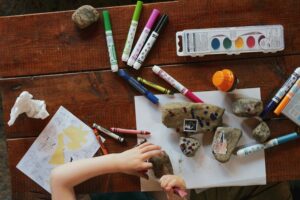 A photo of a child being creative at a big desk covered in art materials