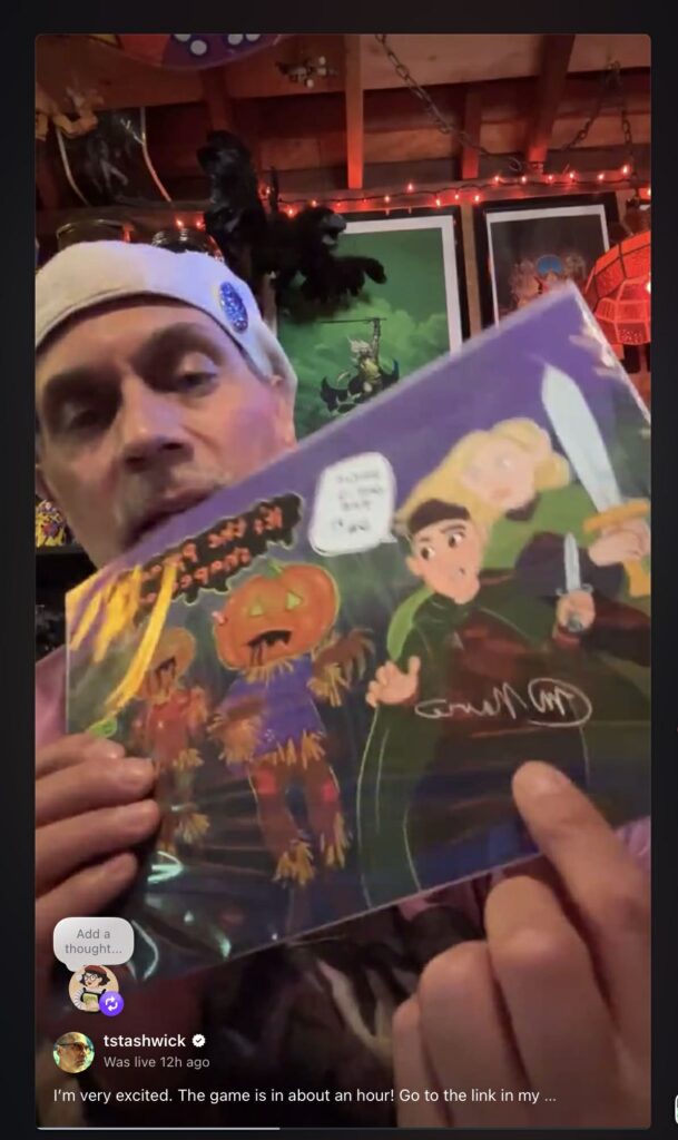 A screen shot of Actor Todd Stashwick during a preview live stream, he is holding up the art print by Lottie Thomson and pointing to Melissa's signature. 